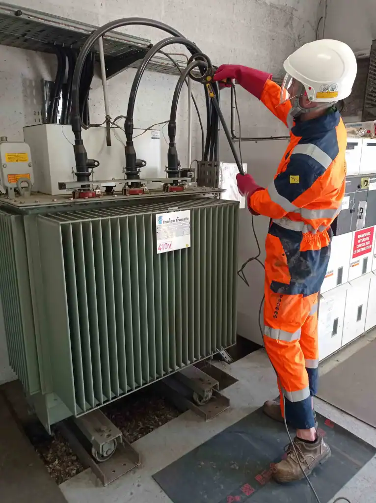 Technicien posant la pince d'un générateur sur un câble électrique pour la détection électromagnétique des réseaux